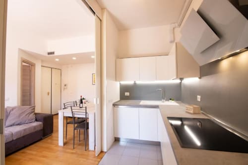 Moderna cucina e living dell'appartamento Dimore Verona con mobili bianchi e vista sulla città