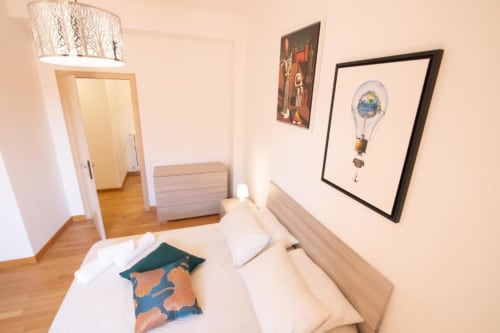 Camera luminosa dell'appartamento Dimore Verona con pavimenti in legno, letto, quadro mongolfiera e arredamento moderno.