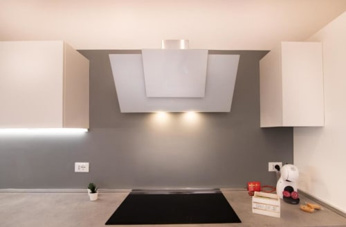 Cucina moderna dell'appartamento di Verona con rivestimento grigio, pensili bianchi e cappa in acciaio inox