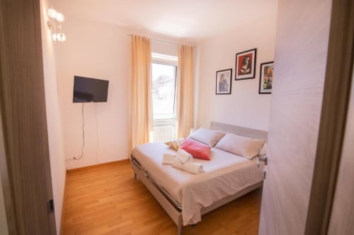 Camera moderna dell'appartamento Dimore Verona a Verona con letto queen, TV e balcone con vista città