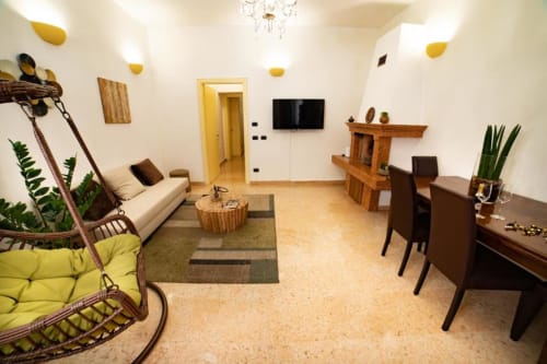 Appartamento moderno a Verona con sedia swing, divano beige, tavolo da pranzo, scaffali in legno e dettagli gialli
