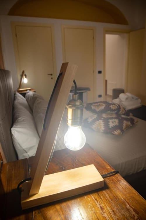 Lampada da tavolo in legno moderno che illumina la camera da letto dell'appartamento Dimore Verona, con soffitto a volta