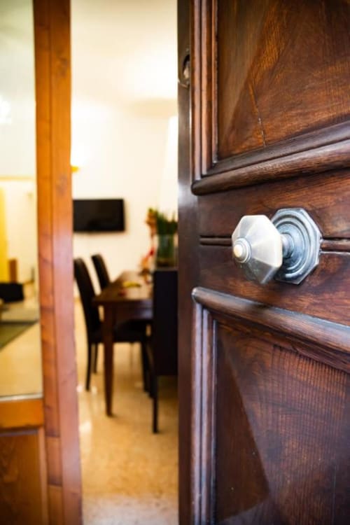 Pomello bianco su porta in legno dell'appartamento Dimore Verona in Italia, che si apre sulla zona pranzo