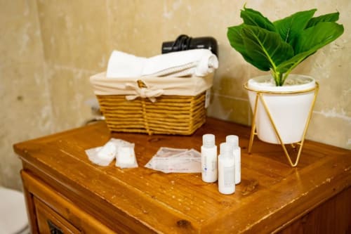 Accessori bagno dell'appartamento Dimore Verona: cesto intrecciato con asciugamani, pianta in vaso e articoli da toeletta su tavolo in legno
