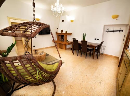 Ampio appartamento Dimore Verona con sedie sospese in vimini, tavolo da pranzo, lampadario e pavimentazione in sughero