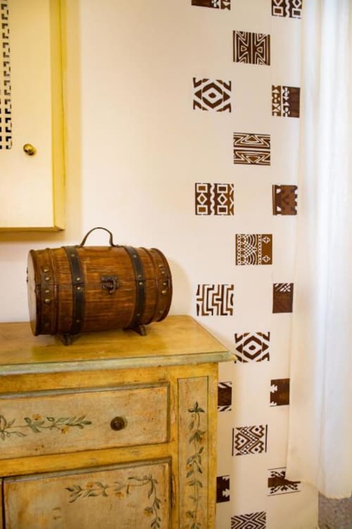 Baule in legno vintage su comò giallo nell'appartamento Dimore Verona, con decorazioni murali geometriche