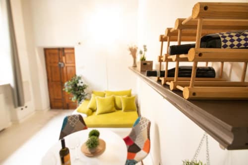 Accogliente appartamento Dimore Verona con divano giallo, letto a castello in legno, tavolo rotondo e vista sul giardino