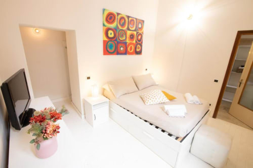 Camera da letto moderna a Dimore Verona con letto, TV, opere d'arte colorate e fiori nell'appartamento veronese