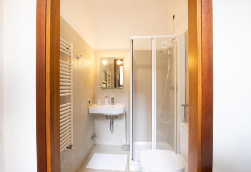 Bagno moderno dell'appartamento Dimore Verona con doccia, lavabo su colonna, scaldasalviette e WC