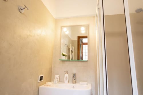 Bagno moderno dell'appartamento Dimore Verona con lavabo bianco, specchio illuminato e box doccia a Verona