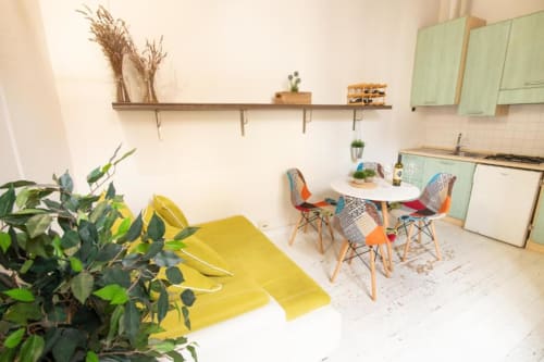 Cucina di appartamento Dimore Verona moderna con mobili menta, zona pranzo, piante in vaso e sedute con accenti gialli