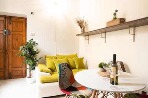Luminoso appartamento moderno a Dimore Verona con divano giallo, tavolo da pranzo bianco e vista sul giardino