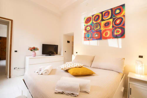 Camera da letto moderna con arte astratta colorata, biancheria crema e vista giardino presso Dimore Verona a Verona