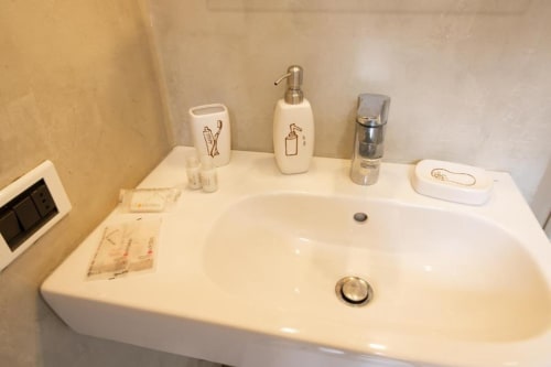 Mobile bagno a Dimore Verona con lavabo bianco, dispenser di sapone e accessori nell'appartamento veronese.