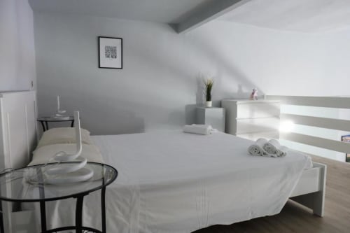 Camera da letto moderna a Dimore Verona con letto bianco, arredamento minimalista e luce naturale a Verona