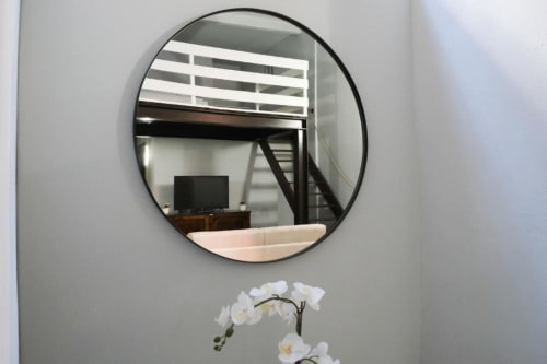 Specchio rotondo sopra orchidee bianche nell'appartamento Dimore Verona a Verona
