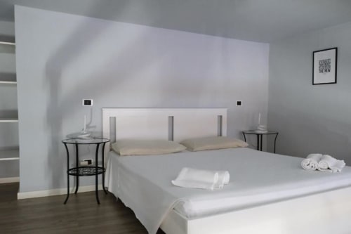 Camera moderna a Dimore Verona con letto bianco, comodini e arredamento minimalista nell'appartamento di Verona