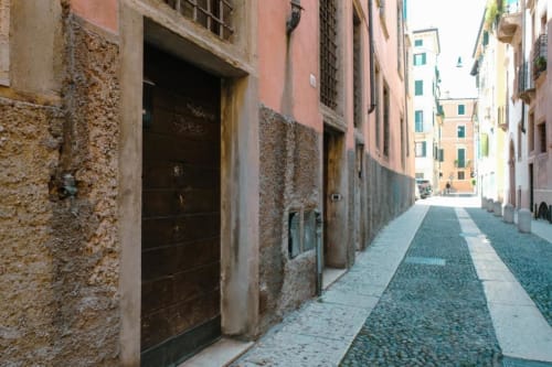 Stretto vicolo lastricato a Verona con edifici storici e porte in legno presso Dimore Verona