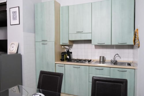 Angolo cottura moderno presso Dimore Verona a Verona: mobili verde menta, fornello a gas, lavello e zona pranzo