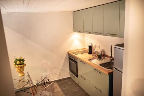 Cucina moderna nell'appartamento Dimore Verona a Verona. Dispone di piano di lavoro in legno, armadi bianchi, elettrodomestici in acciaio inox.