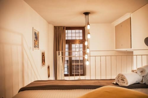 Camera moderna a Dimore Verona con illuminazione a sospensione, ringhiera in metallo e asciugamani arrotolati sul letto