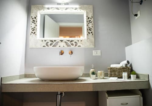 Lavabo moderno nell'appartamento Dimore Verona con vasca bianca, specchio ornamentale e piano rivestito