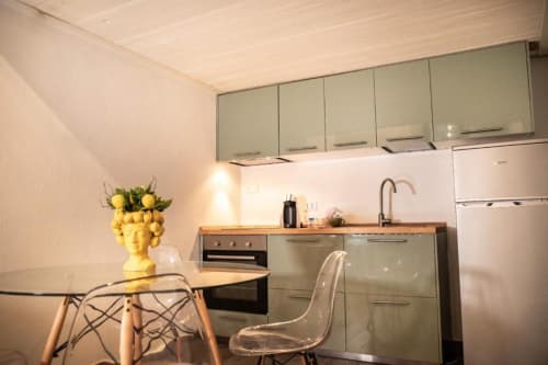 Cucina moderna nell'appartamento Dimore Verona con mobili verde, piani in legno e tavolo da pranzo con frutta gialla