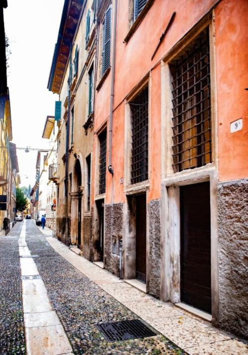 Stretto vicolo di ciottoli nel centro storico di Verona con edifici colorati, ideale per gli ospiti di Dimore Verona alla scoperta della città