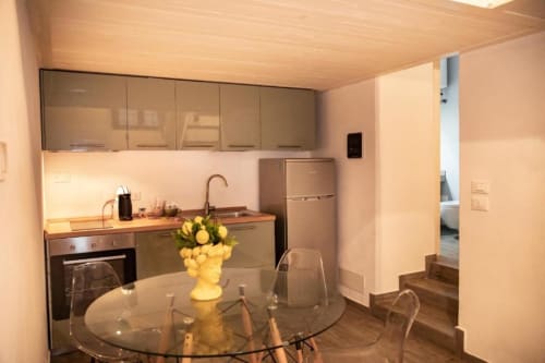 Cucina moderna dell'appartamento a Dimore Verona con zona pranzo, tavolo in vetro, fiori gialli e elettrodomestici in acciaio