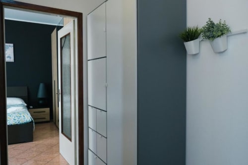 Corridoio moderno a Dimore Verona con piante in vaso, parete accent scura e vista della camera da letto attraverso la porta