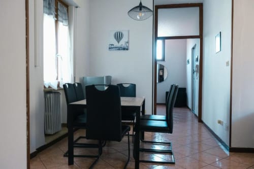Zona pranzo dell'appartamento Dimore Verona con sedie nere, tavolo, lampada a sospensione e vista dalla finestra