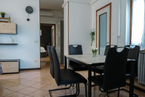 Zona pranzo moderna dell'appartamento Dimore Verona con sedie nere, tavolo in pietra e vista sui monumenti di Verona, Italia