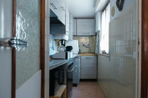 Cucina a galleria stretta dell'appartamento Dimore Verona a Verona con mobili moderni, elettrodomestici in acciaio inox e pareti piastrellate