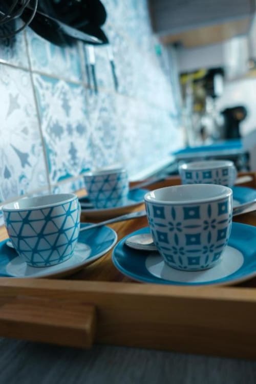 Tazze da tè bianche e blu a motivi su tavolo in legno all'appartamento Dimore Verona, Verona