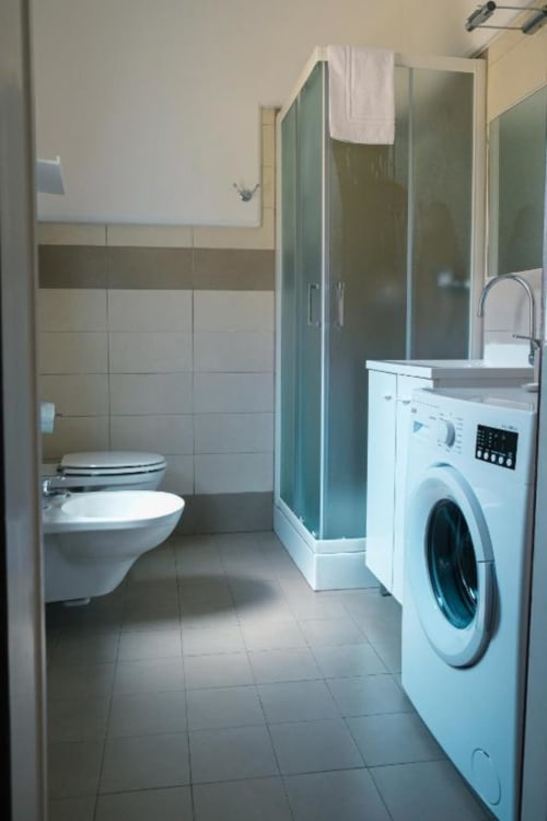 Bagno moderno dell'appartamento Dimore Verona con lavatrice, doccia, bidet e toilette