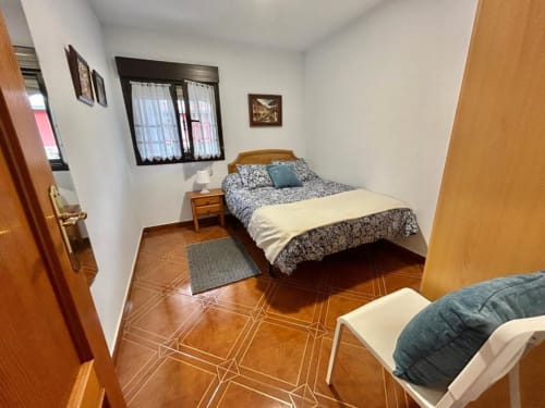 Acogedor dormitorio en el apartamento Las Llaviadas en Ortiguero de Cabrales con cama de madera, vistas a la montaña y suelo cálido de madera.