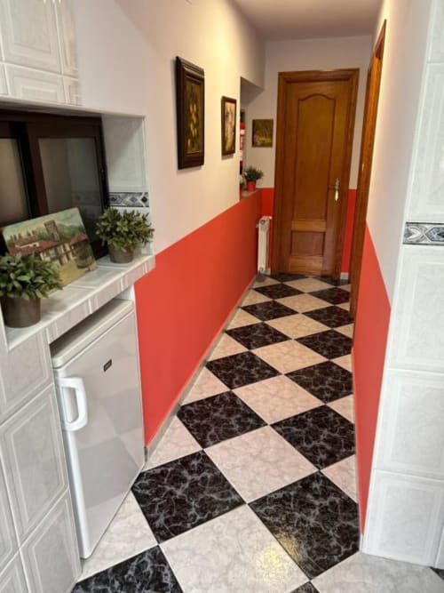 Pasillo del apartamento Las Llaviadas en Ortiguero de Cabrales con paredes rojas y piso de azulejos cuadriculados