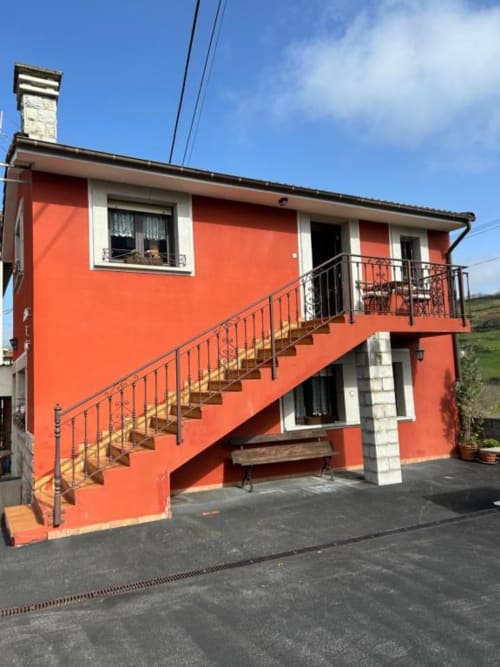 Exterior del apartamento Las Llaviadas en Ortiguero de Cabrales con fachada rojo brillante, escaleras exteriores y vistas a la montaña