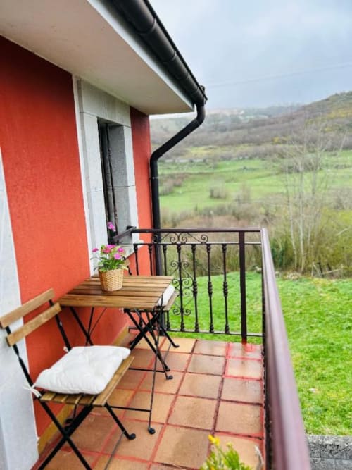 Balcón con vistas a la montaña en Las Llaviadas con mesa, silla, flores y paisaje rural