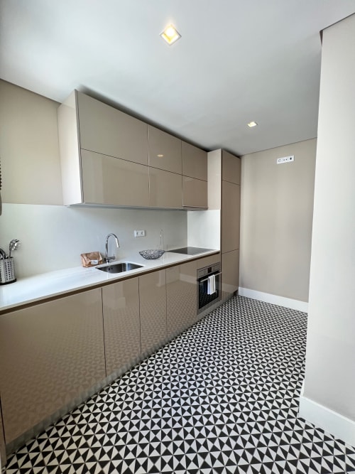 Cozinha moderna no New Oporto Apartments no Porto com armários bege, bancada branca e azulejos geométricos preto e branco