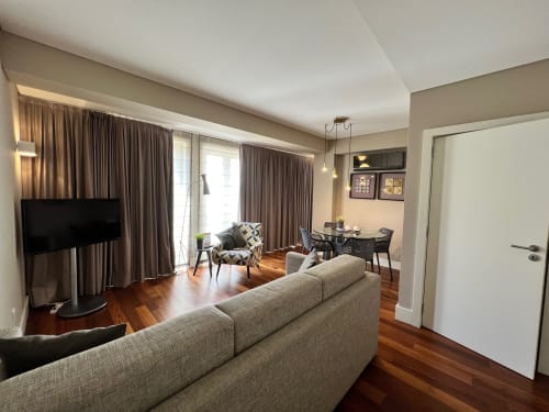 Sala de estar moderna nos Apartamentos New Oporto no Porto com pisos de madeira, sofá bege, TV e área de refeições