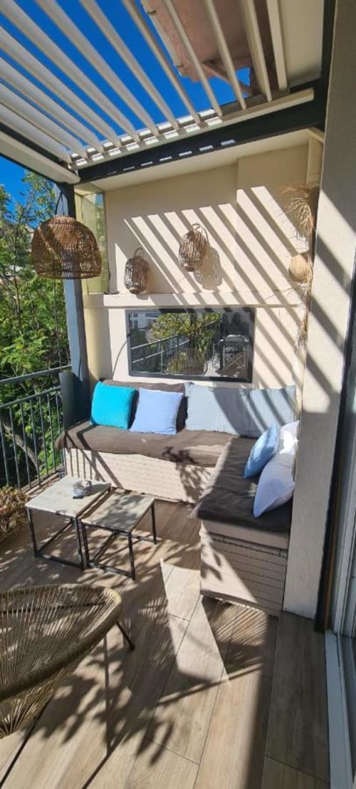 Balcon moderne du Cocon de Chris Marseille avec pergola à lames bleues, mobilier confortable et lumière naturelle