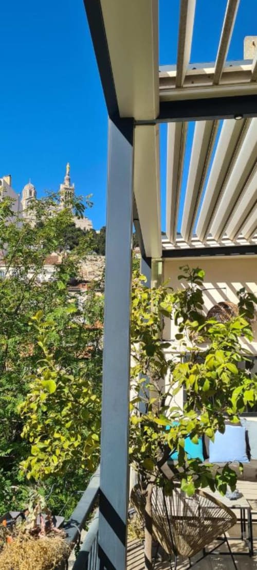 La terrasse du Cocon de Chris à Marseille avec pergola, verdure et vue sur la basilique.