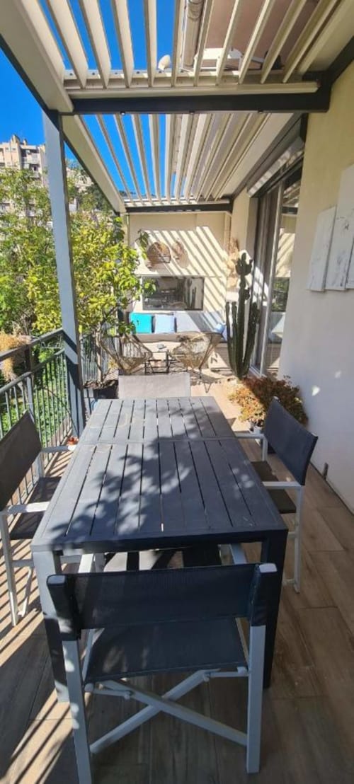 Terrasse moderne de Le Cocon de Chris à Marseille avec pergola à lames et mobilier noir