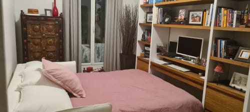 Chambre douillette dans un appartement marseillais avec literie rose, étagères en bois et coin bureau