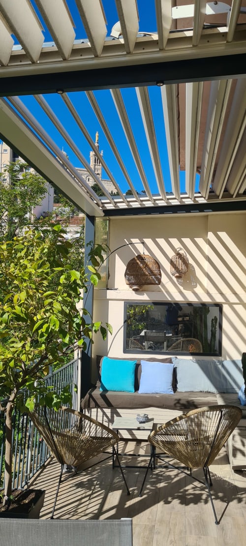 Terrasse moderne du Cocon de Chris avec chaises tressées, pergola bleue et vue sur les monuments de Marseille