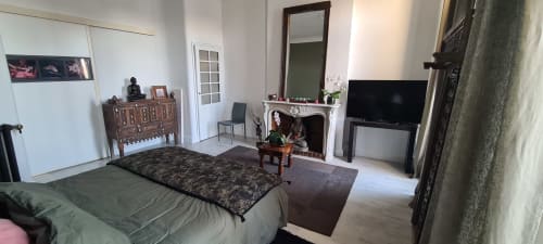 Chambre spacieuse du Cocon de Chris à Marseille avec lit, foyer, TV, miroir et mobilier en bois