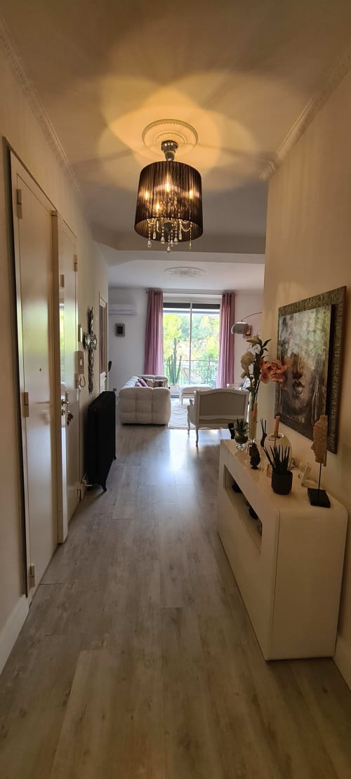 Élégant couloir du Cocon de Chris à Marseille, avec lustre, mobilier blanc et décoration moderne