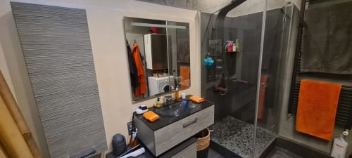 Salle de bain moderne de l'appartement Le Cocon de Chris à Marseille avec vasque noire, miroir, douche à l'italienne et accents orange