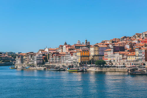 Edifícios coloridos à beira do rio Douro no Porto com barcos, ideais para New Oporto Apartments